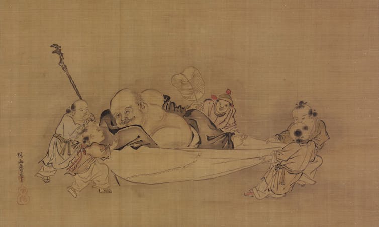 A monk lying on a bed while children tug at the sheet and play with him.