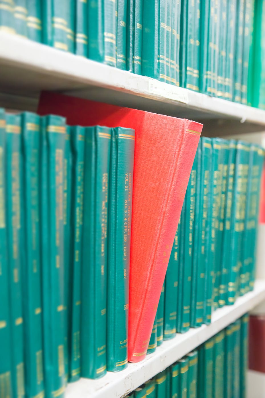 A red journal seen tipping off a shelf.