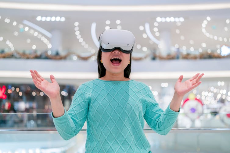 A woman using a VR headset standing in a shopping mall