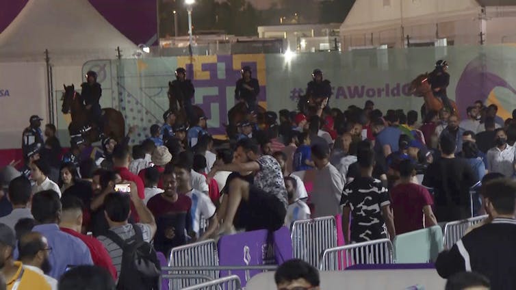 armed police on horseback watch over a crowd.
