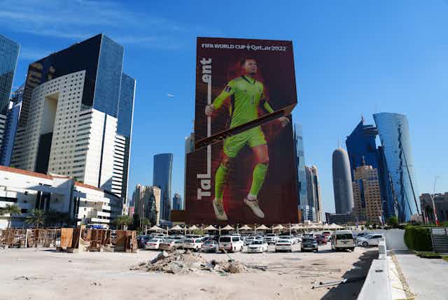 cars parked in front of a billboard with a giant image of a football player in a lime green uniform