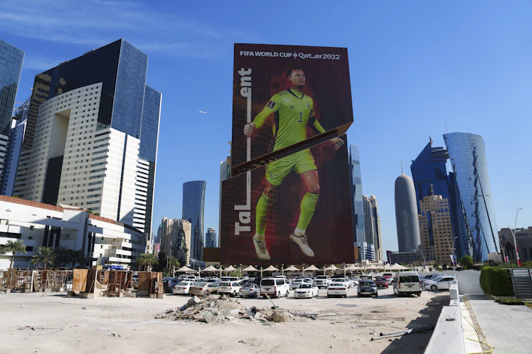 cars parked in front of a billboard with a giant image of a football player in a lime green uniform