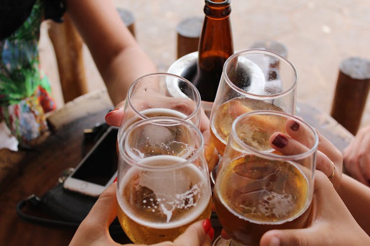 close-up of friends clinking four beers together