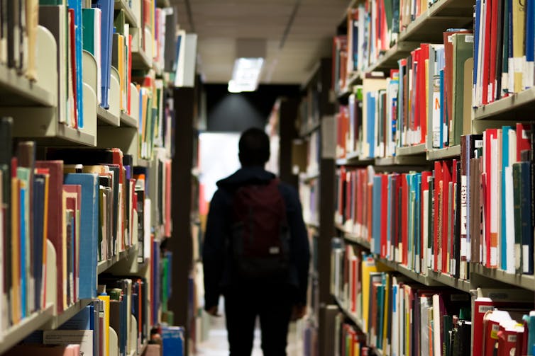 A student walks through library shelves.