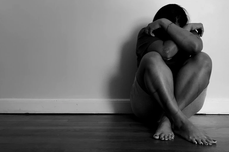 Woman with bruises sitting on the floor at home
