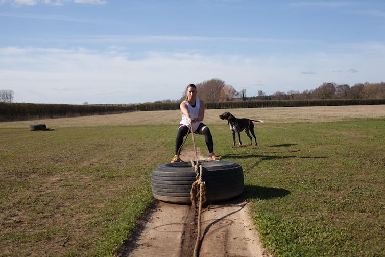 Woman pulling a tyre backwards.