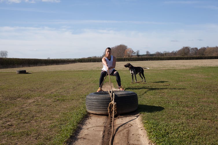 Mujer tirando de un neumático hacia atrás.