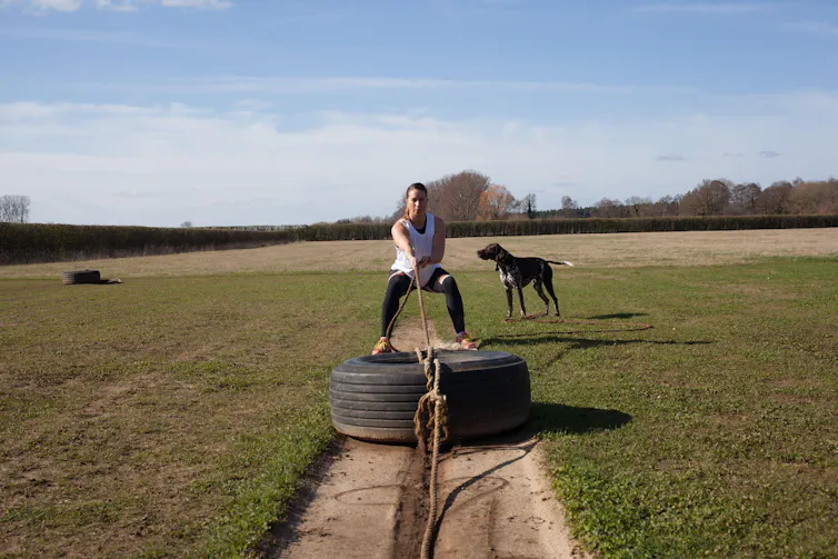 Woman pulling a tyre backwards.