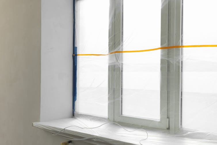 A window and a white window sill covered in plastic film.