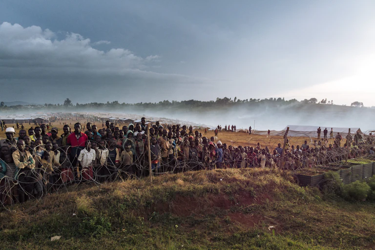Dozens of displaced people gather along the fence of the MONUSCO base in DRC.