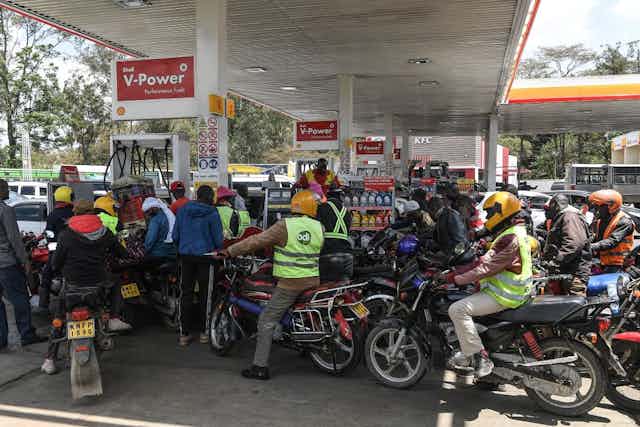 Motorcycle taxis queue for fuel at a petrol station