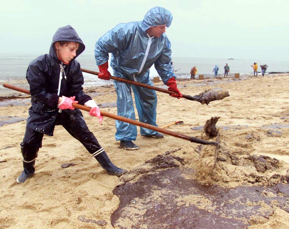 Une enfant et son père nettoient une plage souillée après le naufrage d'un bateau pétrolier en 1999
