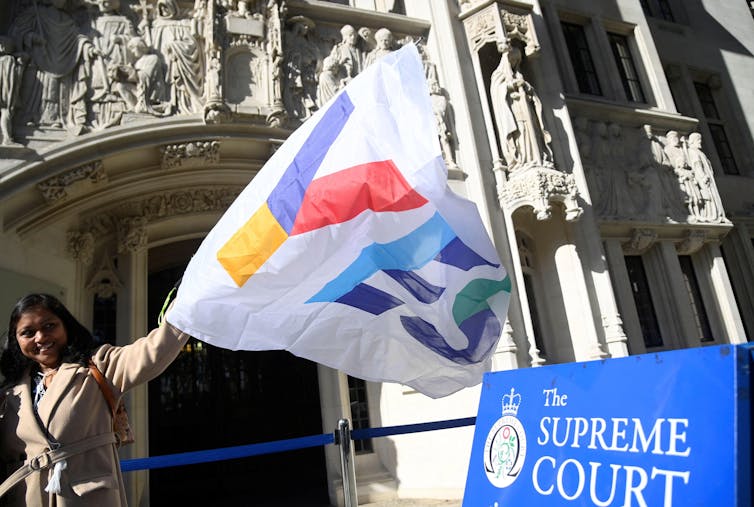 A woman waving a'Yes' flag in front of the supreme court.