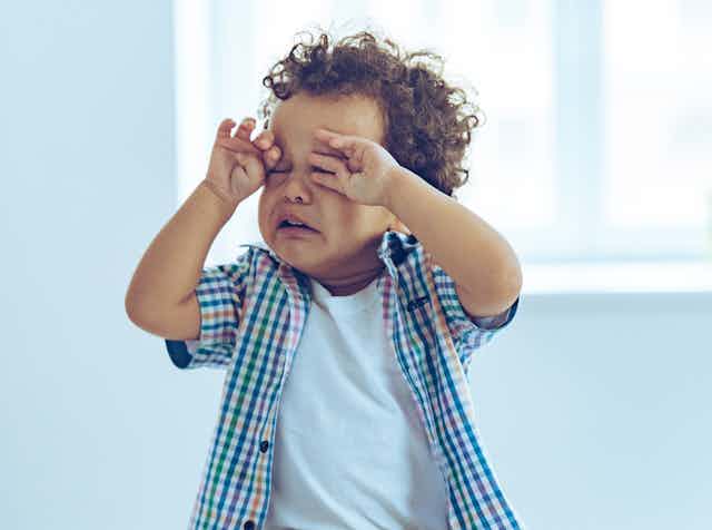 Toddler boy crying and rubbing eyes