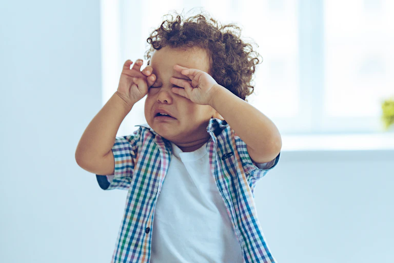 Toddler boy crying and rubbing eyes