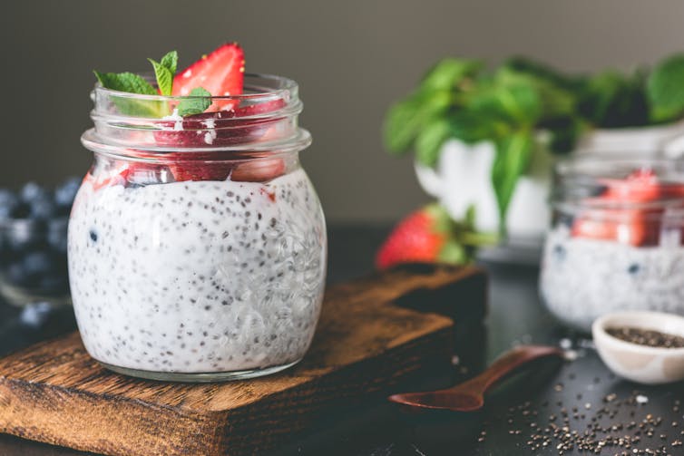 Barattolo di vetro riempito con budino e guarnito con frutta.