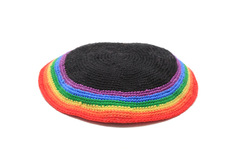 A Jewish head covering for men, stitched with rainbow colors, against a white background.
