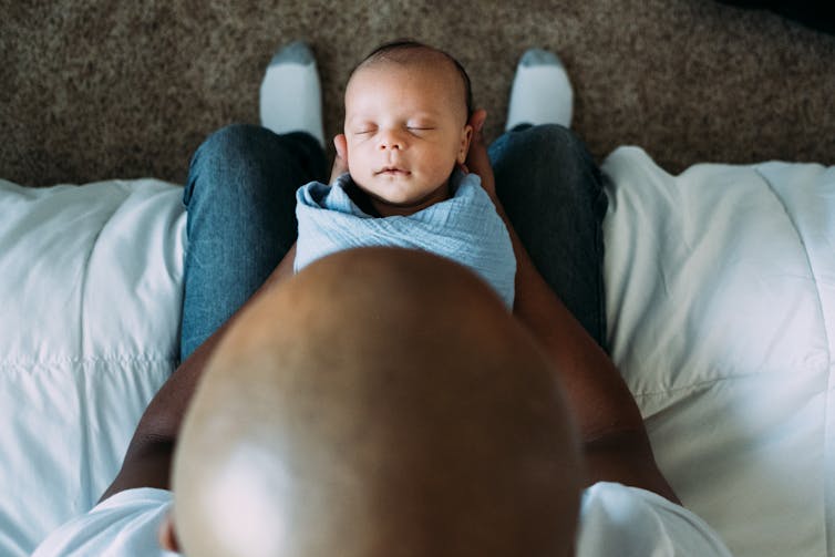 view from above of the shaved head of a man holding a newborn