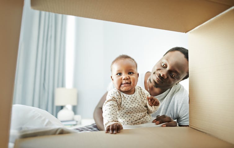 baby and man peeking into a cardboard box