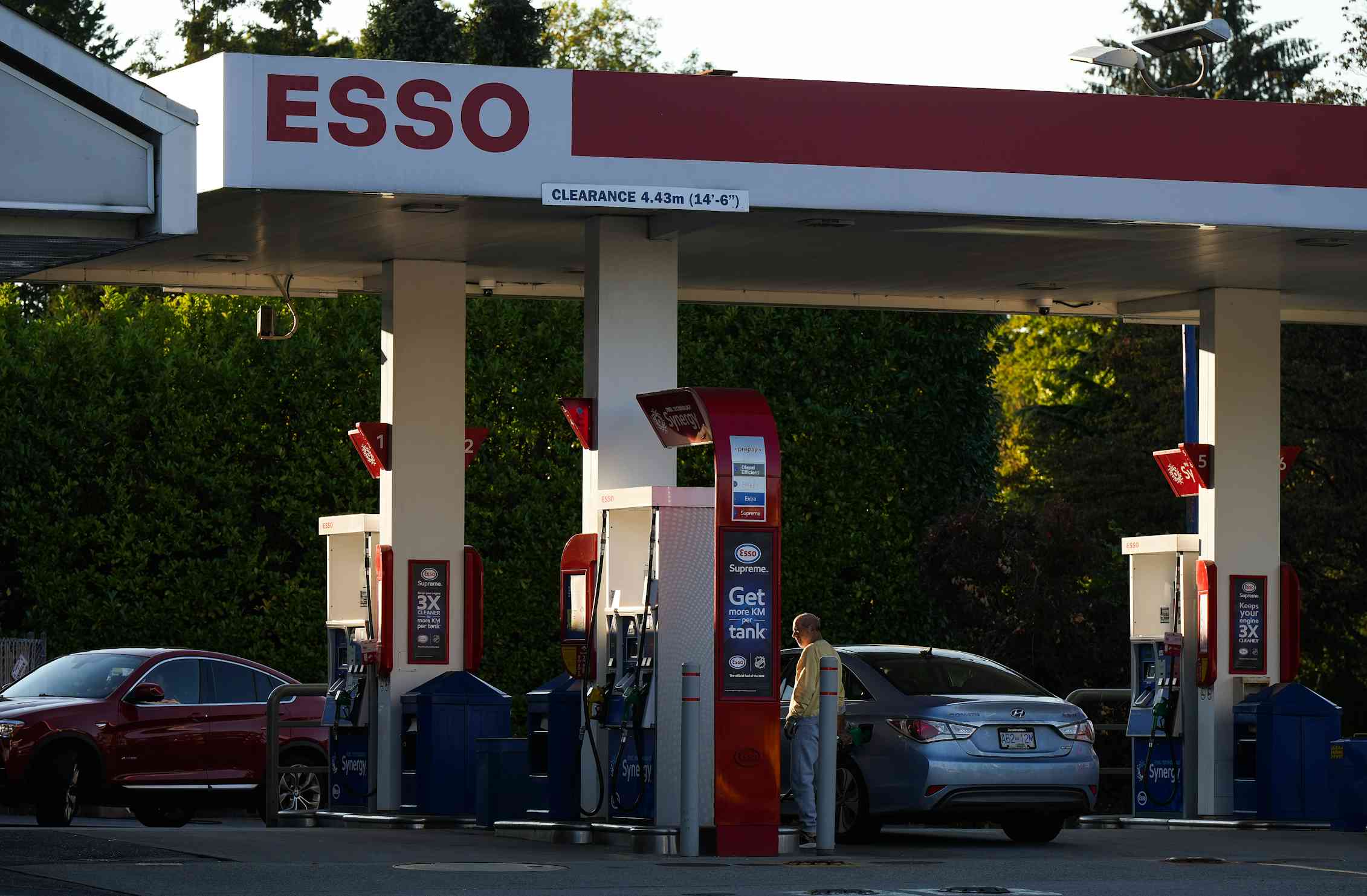 A person fuels up their car at an Esso gas station