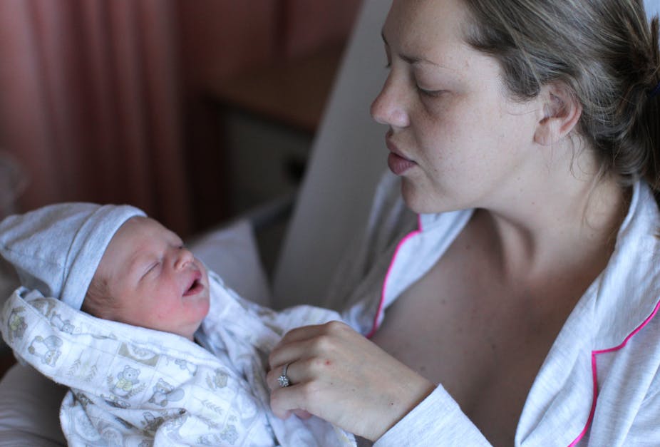 A young woman holds and soothes her newborn baby.