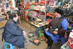 Two people converse in a small market.