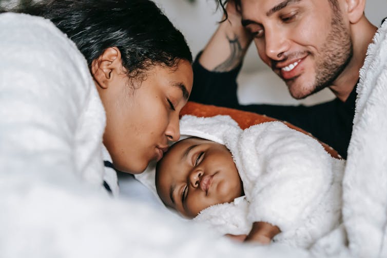 Parents snuggle their newborn baby