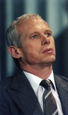 A man wearing a shirt, tie and jackets displays a serious look.