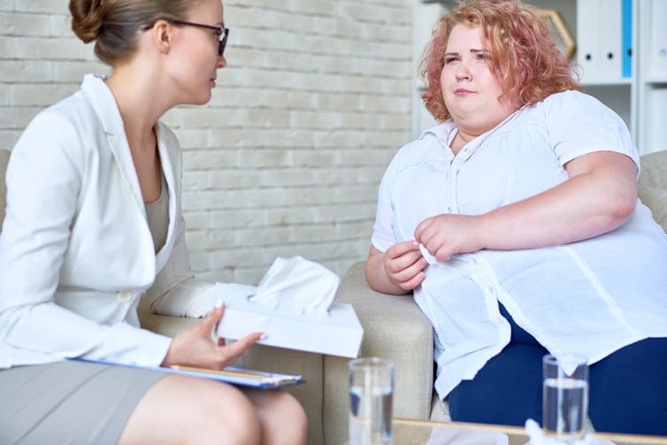 A therapist speaks with a young woman.