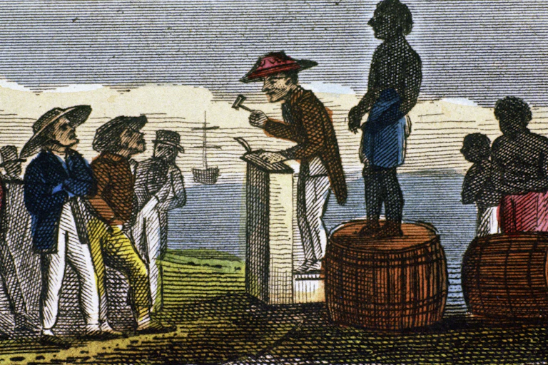 A black man stands on top of a barrel while a white man wearing a large hat with a gavel in his hand stands next to him on a podium.