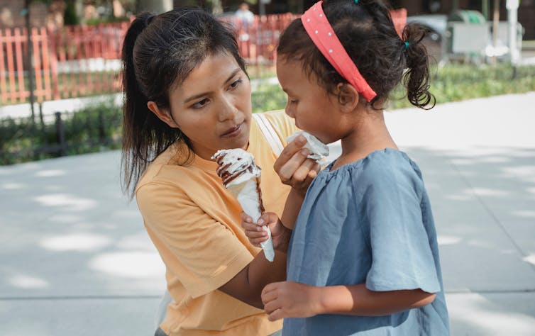 Mother wipes ice cream from her daughter's chin