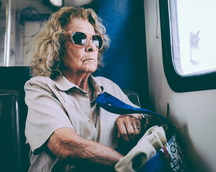 Older woman feels for her keys in a handbag while riding the bus
