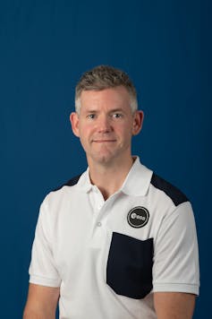 Portrait of a smiling white man in a black and white polo shirt looking at the camera