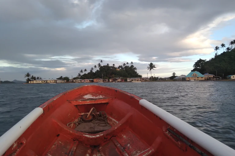 Front of boat approaching a small village on an island