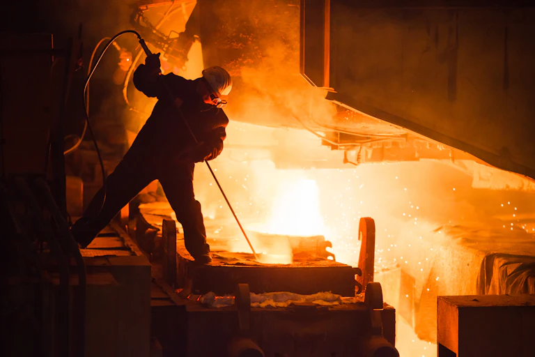 A worker probes the interior of a furnace.
