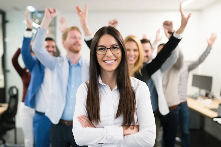 Group of successful business people happy, punching the air, in an office, "leader" in the foreground, smiling.