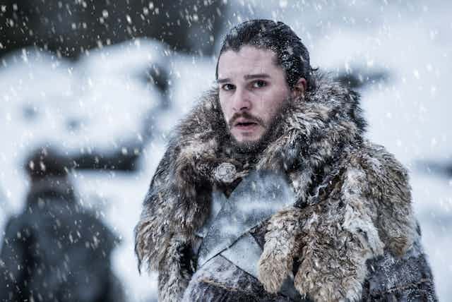 John Snow (Game of Thrones) est sous la neige, habillé de chaudes fourrures.