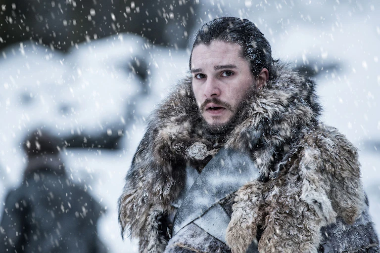John Snow (Game of Thrones) est sous la neige, habillé de chaudes fourrures.