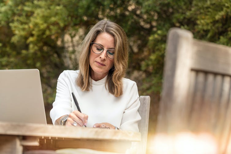 woman writing something at outdoor table