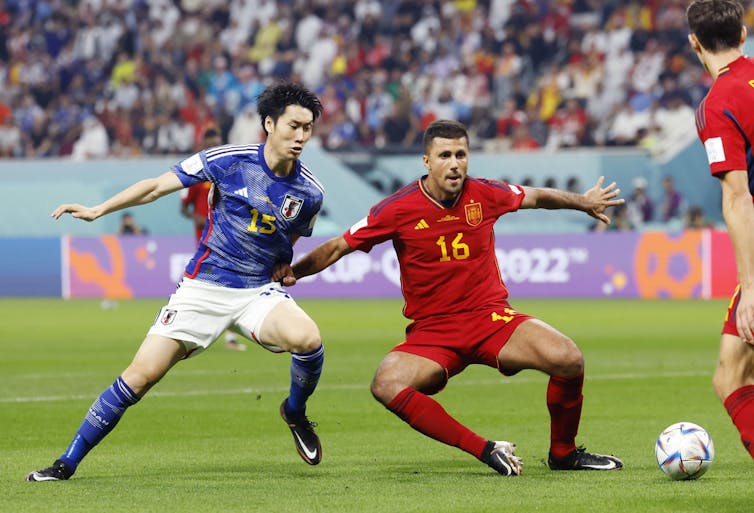 Spain's Rodri (16) and Japan's Daichi Kamada vie for the ball during the first half of a World Cup Group E football match at Khalifa International Stadium