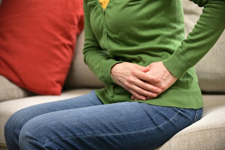 A woman holds her stomach in pain.