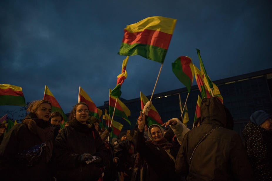 Women carrying red, yellow and green flags.