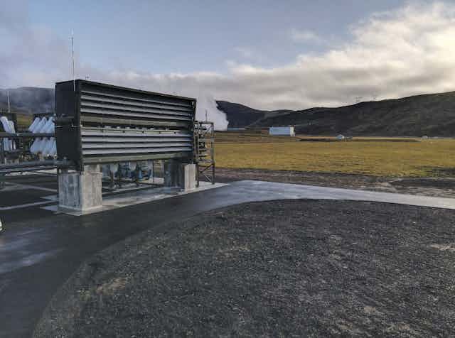 Ventilators stand on a concrete strip against a mountain backdrop.