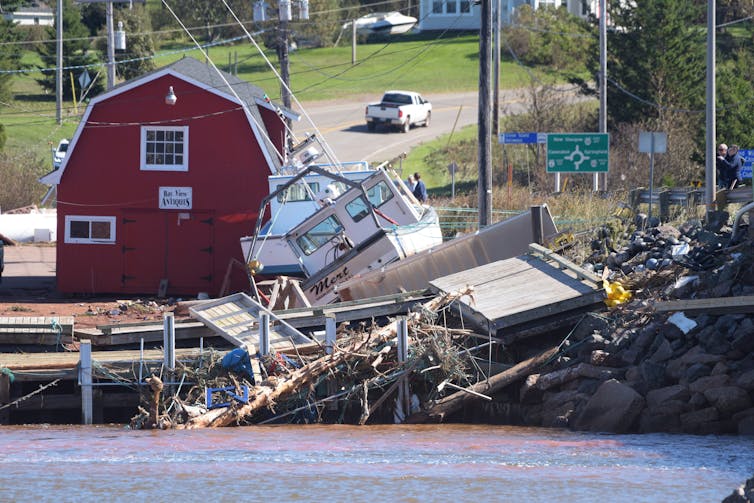 A collapsed dock and an upended boat are seen in an otherwise picturesque harbour.