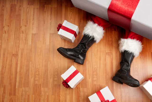 Santa crushed by a massive present with only his two black boots are visible.