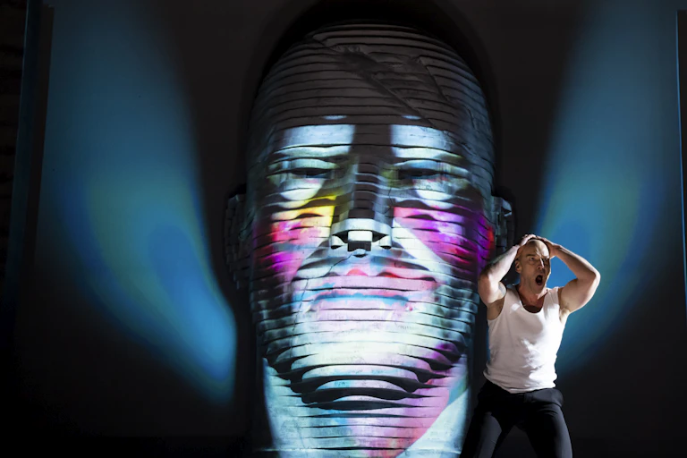 A man sings in front of a giant head