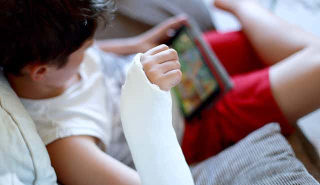 Child with broken arm watching soemthing on a tablet