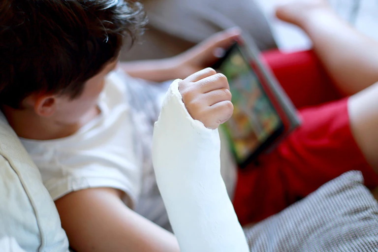 Child with broken arm watching soemthing on a tablet