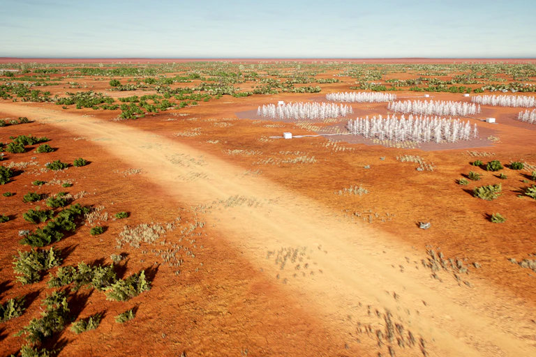 Aerial view of a dirt road in a red desert, with fields of antennae.