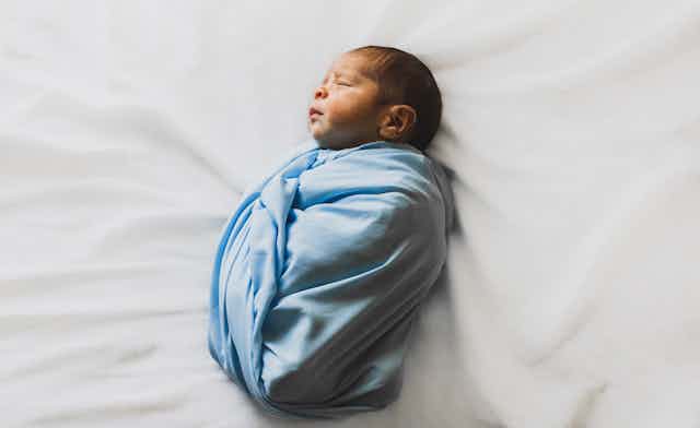 Newborn baby in a blue swaddle